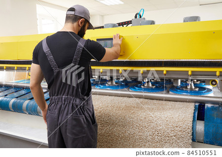Man operating carpet automatic washing machine in professional laundry service 84510551