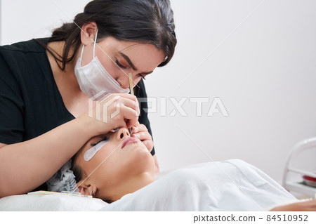 Eyelash Extension Procedure. Woman Eye with Long Eyelashes 84510952