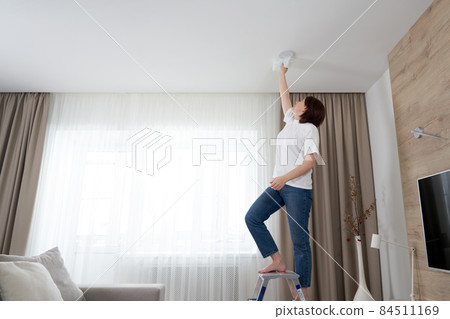 Woman cleaning ceiling with a mop. Housewife cleaning living room 84511169