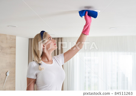 Maid woman holding mop pile, cleaning ceiling in living room. House cleaning service concept. 84511263