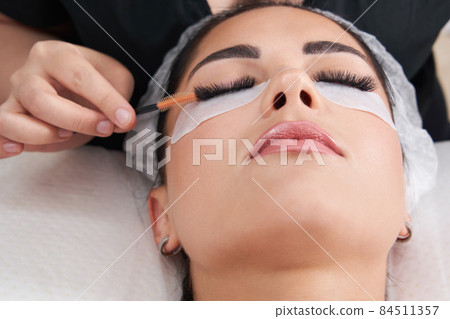 Cosmetologist making eyelash extention and correction using brush Cosmetologist making eyelash extention and correction using brush 84511357