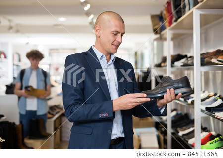 Smiling man looking for classic shoes in shoe store Smiling man looking for classic shoes in shoe store 84511365