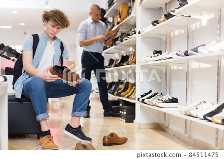 Teen boy trying on classic shoes at shoe store 84511475