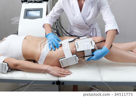 Beautiful woman getting electro stimulation therapy. Laser lipo equipment. Cosmetic fat reduce treatment. Anti cellulite procedure 84511773