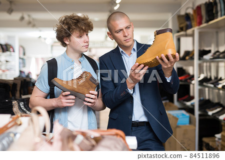 Man and teenage boy choosing demi-season shoes in store Man and teenage boy choosing demi-season shoes in store 84511896