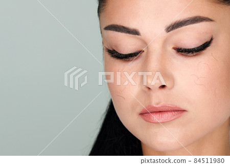 Young Woman with artificial eyelash loss problem. Fallen eyelashes all over the face. Needs eyelash correction 84511980