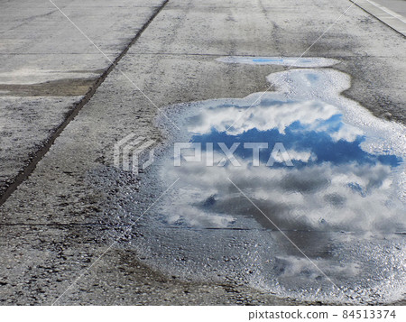 Blue sky reflected in a puddle Blue sky reflected in a puddle 84513374