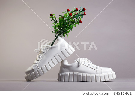 white sneakers and branch with berries. fashion shoes still life 84515461