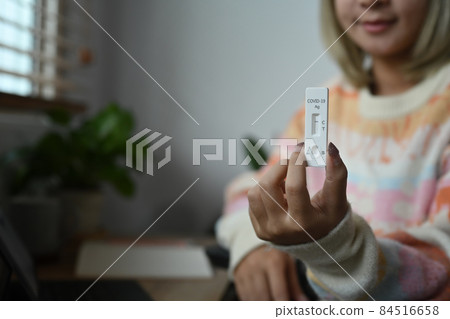 Smiling young woman showing COVID 19 antigen test kit with negative result. Smiling young woman showing COVID 19 antigen test kit with negative result. 84516658