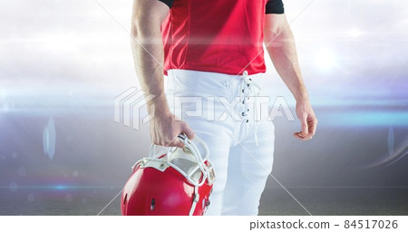 Midsection of muscular male american football player holding helmet against illuminated stadium Midsection of muscular male american football player holding helmet against illuminated stadium 84517026