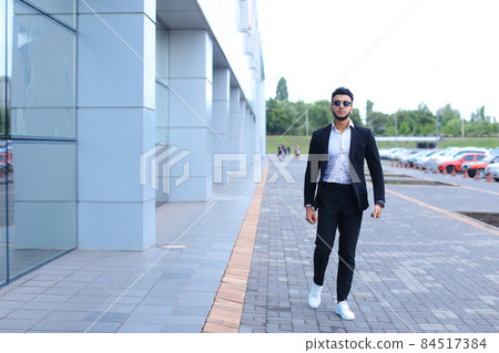 Arabic guy in business center stands smiling walking slow Arabic guy in business center stands smiling walking slow 84517384
