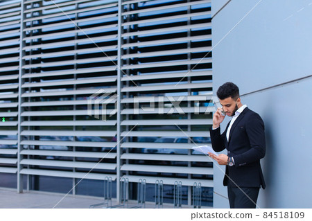 Handsome arabic man talks on mobile phone in business center Handsome arabic man talks on mobile phone in business center 84518109