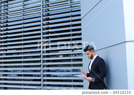 Handsome arabic man talks on mobile phone in business center Handsome arabic man talks on mobile phone in business center 84518133