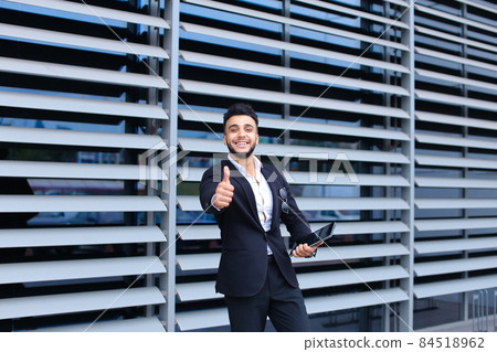 Arabic guy in business center stands smiling Arabic guy in business center stands smiling 84518962