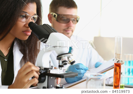 A black woman and a white man are working in the laboratory 84519973