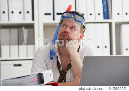 A man wearing a scuba diver's mask is sitting in the office 84520025