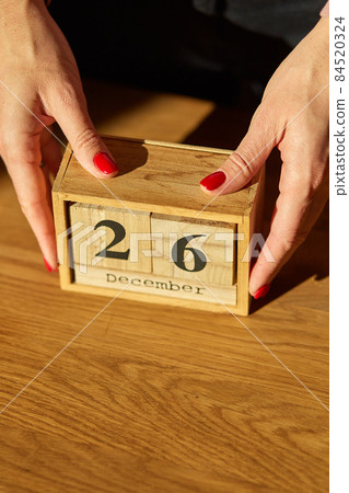 Woman hand change, sets the date on the wooden calendar on 26 December 84520324