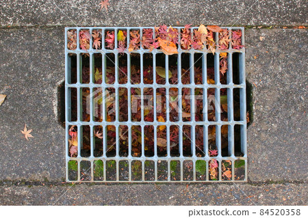 Gutter with lots of fallen leaves 84520358