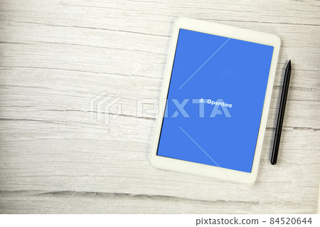 The Netherlands, December 2021 Opensea app on white digital tablet on wooden table with copy space, market place for non-fungible tokens NFT digital art The Netherlands, December 2021 Opensea app on white digital tablet on wooden table with copy space, market place for non-fungible tokens NFT digital art 84520644