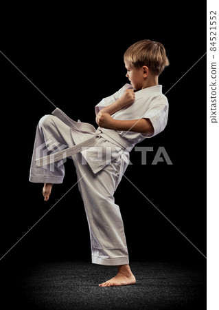 Full-length portrait of boy training martial arts isolated over black background Full-length portrait of boy training martial arts isolated over black background 84521552