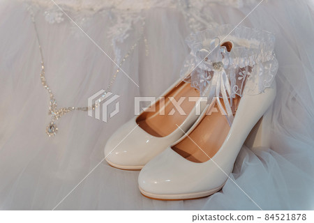 Wedding accessories for the bride, luxury ring pillow and garter, classic leather shoes, elegance veil with lace. Selective focus. Bride's shoes and Bride's garter with bride and groom wedding rings Wedding accessories for the bride, luxury ring pillow and garter, classic leather shoes, elegance veil with lace. Selective focus. Bride's shoes and Bride's garter with bride and groom wedding rings 84521878