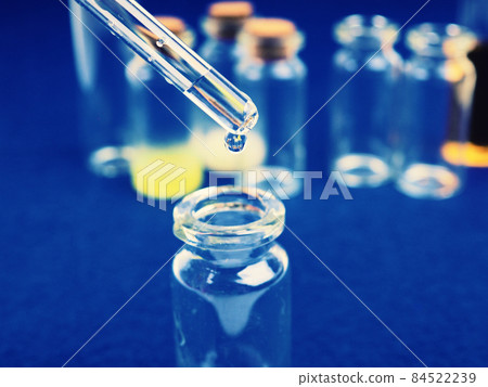 drop of liquid from a pipette into a medical bottle, research concept, new drugs and science, on a bright pink, blue and purple background drop of liquid from a pipette into a medical bottle, research concept, new drugs and science, on a bright pink, blue and purple background 84522239