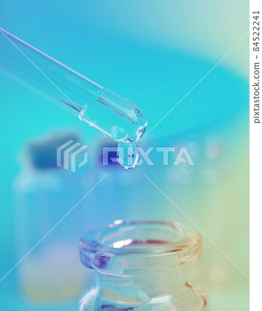 drop of liquid from a pipette into a medical bottle, research concept, new drugs and science, on a bright pink, blue and purple background drop of liquid from a pipette into a medical bottle, research concept, new drugs and science, on a bright pink, blue and purple background 84522241