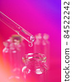 drop of liquid from a pipette into a medical bottle, research concept, new drugs and science, on a bright pink, blue and purple background 84522242