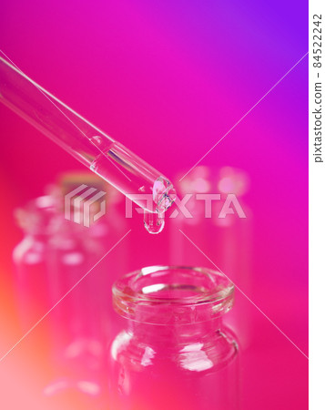 drop of liquid from a pipette into a medical bottle, research concept, new drugs and science, on a bright pink, blue and purple background drop of liquid from a pipette into a medical bottle, research concept, new drugs and science, on a bright pink, blue and purple background 84522242