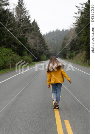 woman in autumn coat hitchhiking walking on road, hitch hiking woman in autumn coat hitchhiking walking on road, hitch hiking 84522536