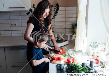 mother and son prepare fresh vegetables for salad at lunch in the kitchen mother and son prepare fresh vegetables for salad at lunch in the kitchen 84522967