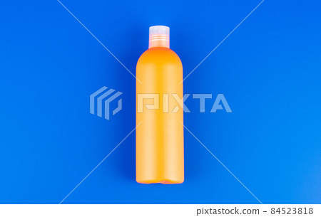 orange shampoo bottle on blue background, toiletries 84523818