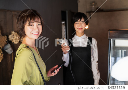 A female photographer who makes a smartphone payment at a cafe "Western confectionery store sentiment" 84523839