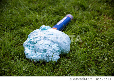 An exploded cylinder with construction foam on the grass. Balloon defect, close-up An exploded cylinder with construction foam on the grass. Balloon defect, close-up 84524374