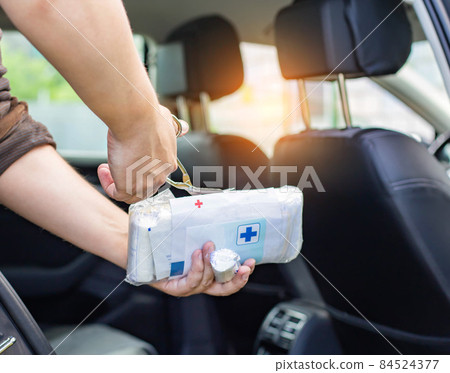 a man opens a bandage in a car first aid kit with scissors. Accident first aid concept 84524377