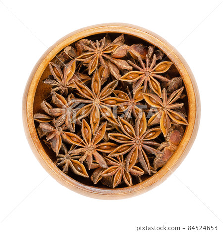 Star anise fruits and seeds, in a wooden bowl. Also known as staranise, star aniseed or badian. Dried, star-shaped pericarps of Illicium verum, containing anethole, a spice with intense anise flavor. Star anise fruits and seeds, in a wooden bowl. Also known as staranise, star aniseed or badian. Dried, star-shaped pericarps of Illicium verum, containing anethole, a spice with intense anise flavor. 84524653