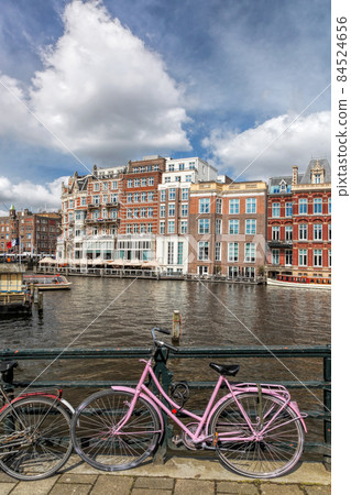 Amsterdam city with bikes against main canal during springtime in Netherlands. Amsterdam city with bikes against main canal during springtime in Netherlands. 84524656