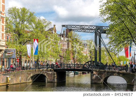 Amsterdam city with old bridge over canal during springtime in Netherlands. 84524657