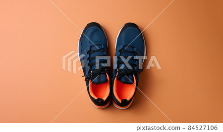 pair of blue textile sneakers on orange background, top view 84527106