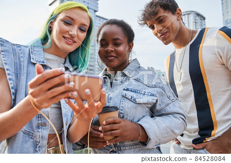 Friends watching something on mobile phone in city 84528084