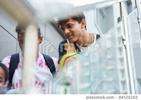 Friends sitting on stairs and watching something 84528103
