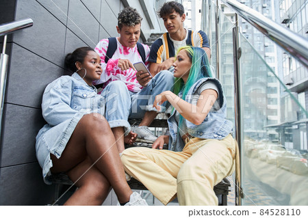 Different races friends resting on metal stairs Different races friends resting on metal stairs 84528110