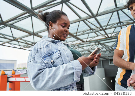 Multiracial woman using her smartphone while standing near her best friends Multiracial woman using her smartphone while standing near her best friends 84528153