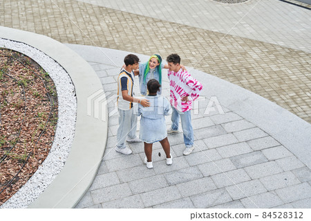 Diverse stylish students embracing and laughing while walking at the street Diverse stylish students embracing and laughing while walking at the street 84528312