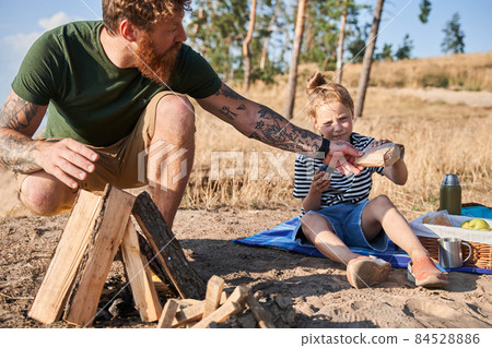 Man making fire and giving cake to daughter 84528886
