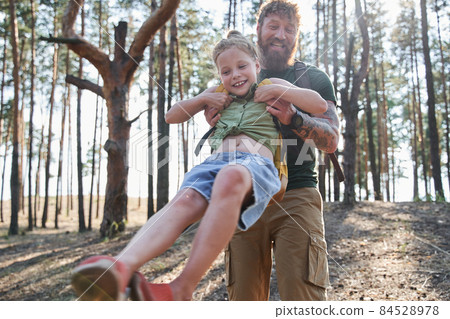 Man spinning his daughter in arms in forest 84528978