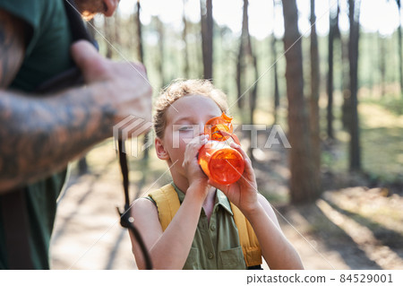 Girl drinking water from bottle in forest 84529001
