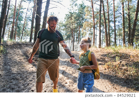 Father walking with daughter on path in forest 84529021