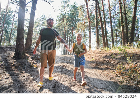 Father walking with daughter on path in forest 84529024