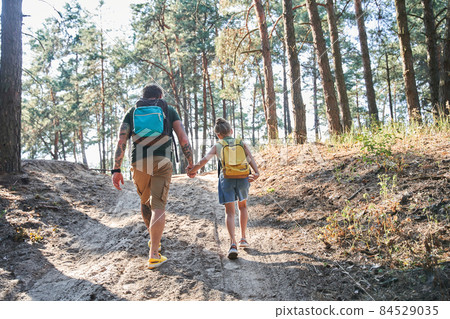 Father walking with daughter on path in forest 84529035